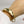 Close-up of hand wearing open cuff polished brass bracelet with organic leaf motif.