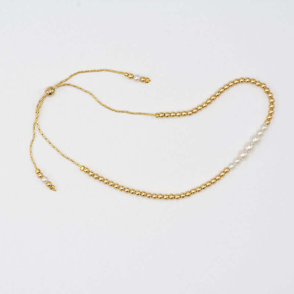 Gold beaded bracelet with pearls at the center and adjustable sliding clasp.