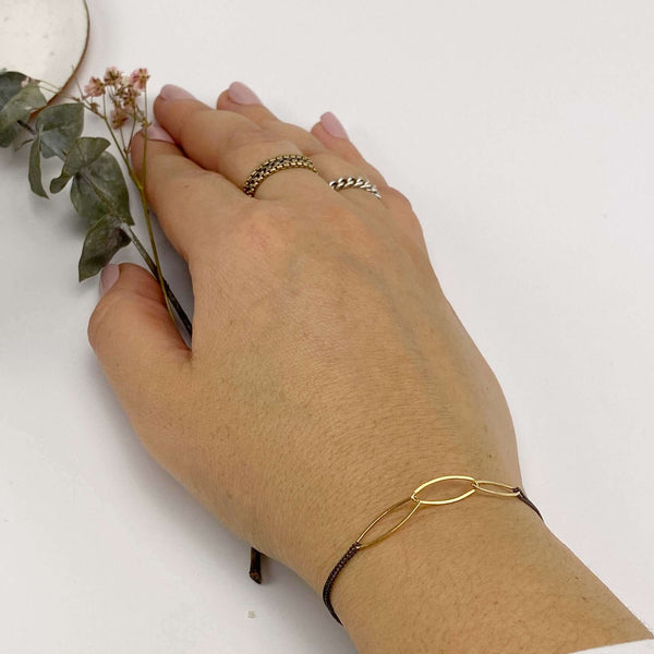 Close-up of hand wearing black oxidized chain bracelet with gold oval links.