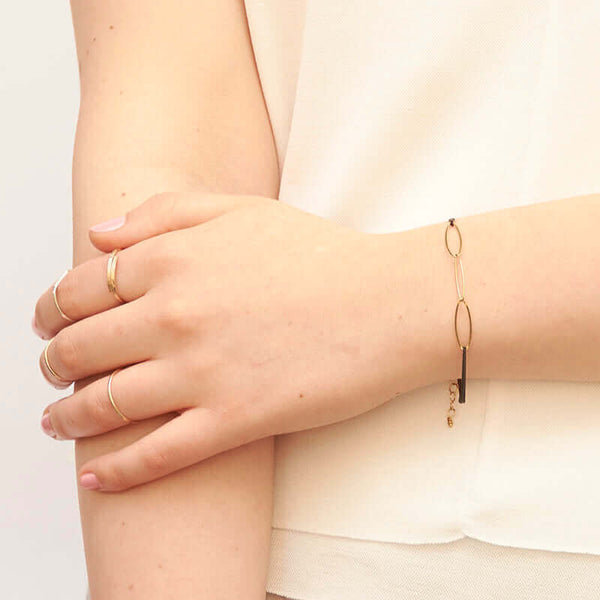 Close-up of arm wearing black oxidized chain bracelet with gold oval links.