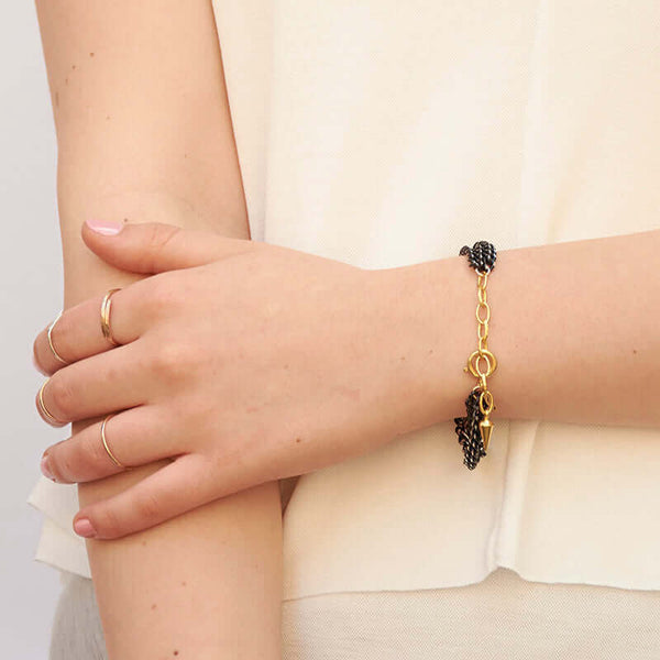 Close-up of arm wearing bracelet with 3 twisted black oxidized chain showing gold links and clasp.