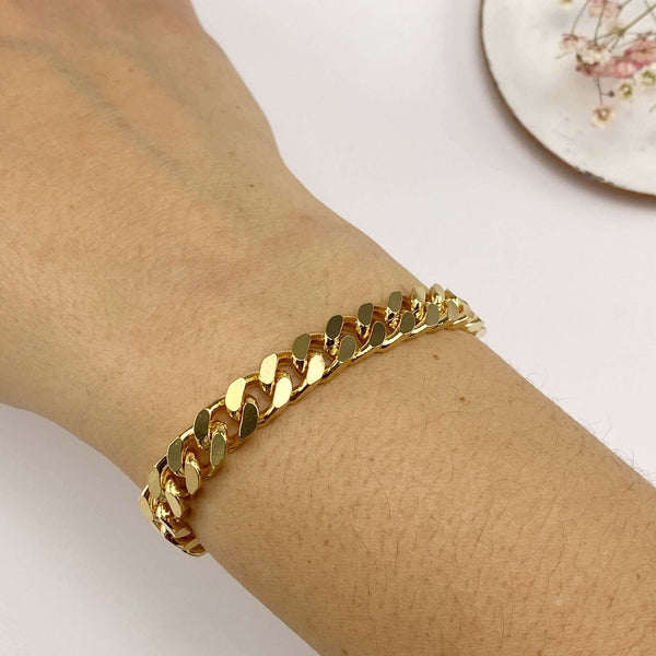 Close-up of hand wearing a chunky gold curb chain bracelet.