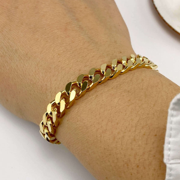 Close-up of hand wearing a chunky gold curb chain bracelet.