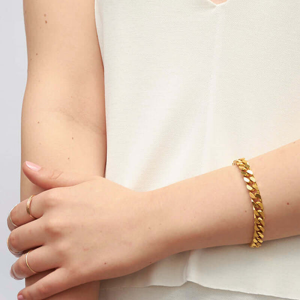 Close-up of arm wearing a chunky gold curb chain bracelet.