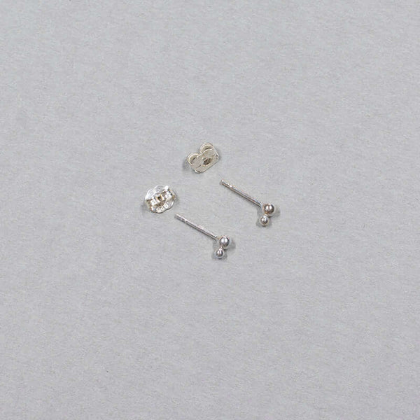 Small silver earrings with two gold stacked beads on a post, shown from side.