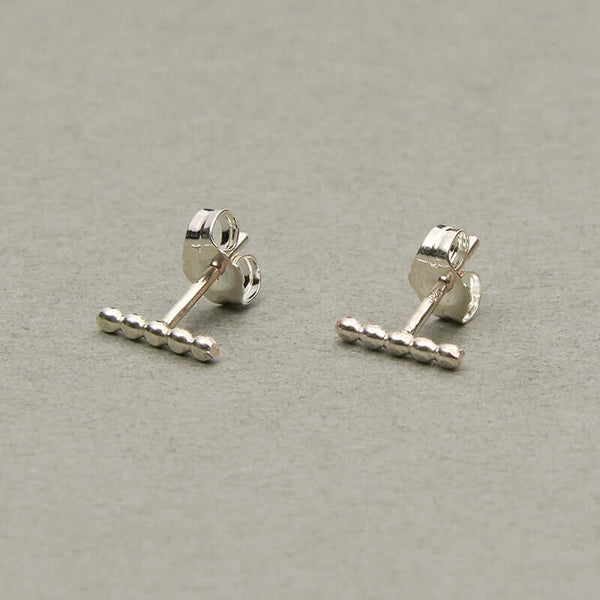 Pair of silver beaded bar earrings on earpost.