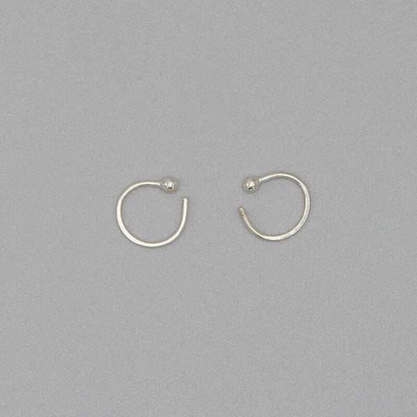 Pair of small silver hoop earring with a tiny ball detail in front, facing in.