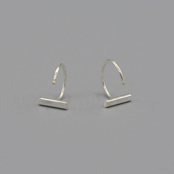 Pair of silver earrings, flat bar in front with curved wire hoop.