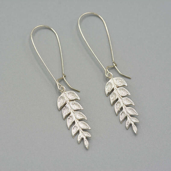 Pair of silver fern leaf shaped earrings on long earwire.