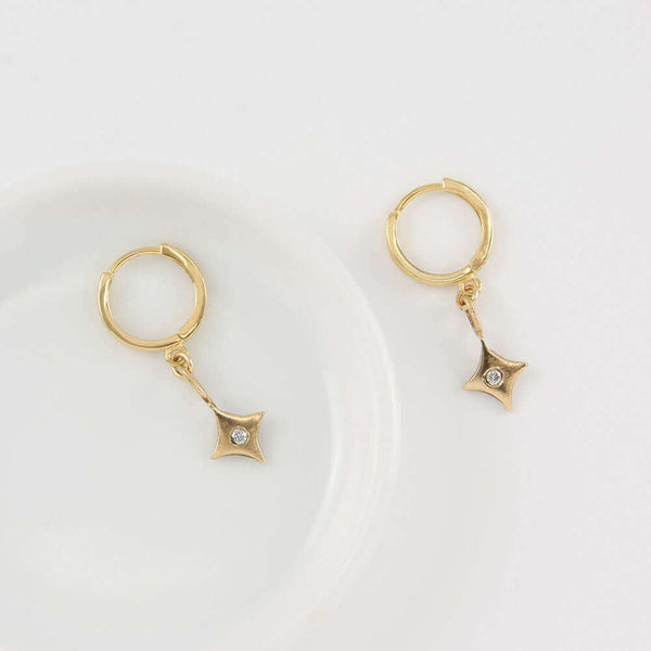 Pair of 4 point gold star earrings on hoop clasp.
