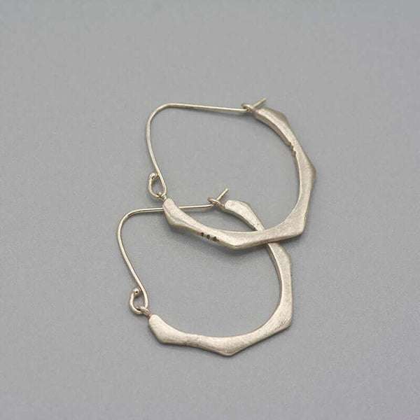 Pair of cast brushed silver hoop style earrings.