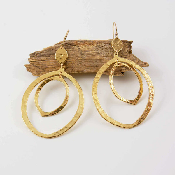 A Pair of Nena Hammered Dangle Earrings Displayed on Driftwood