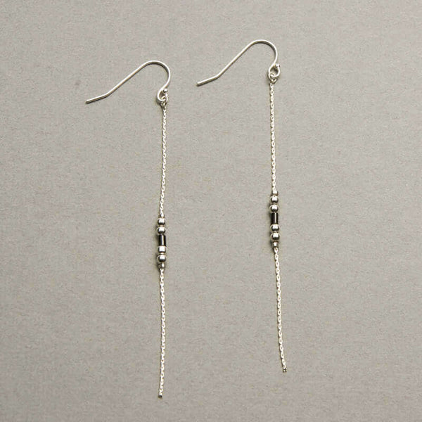 Pair of silver earrings, gold chain with black bead details.