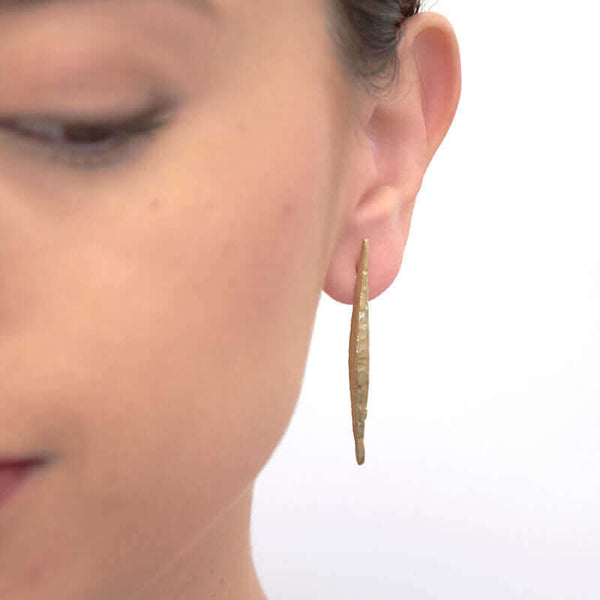 Close-up front view of woman wearing a pair of silver spike earrings on posts.