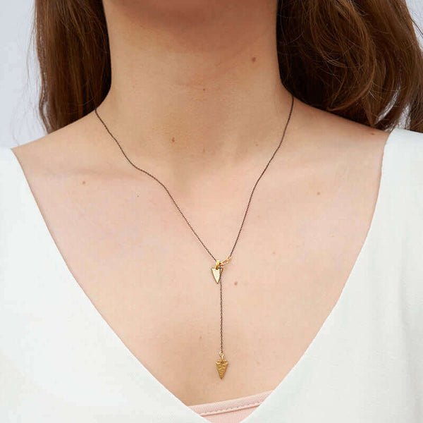 Woman wearing black chain necklace with both brass arrowheads in front.