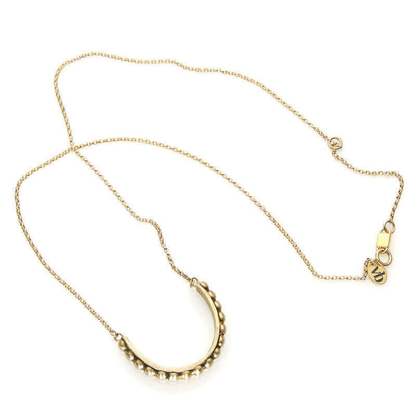 Gold chain with half-circle beaded bar as pendant, laid out showing clasp.