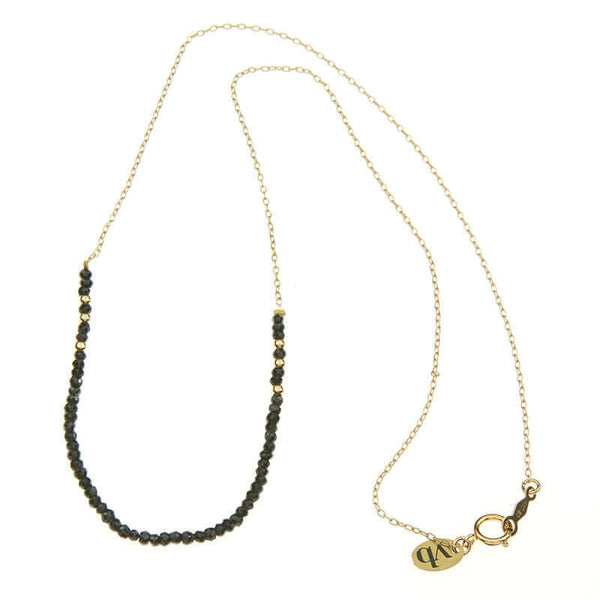 Gold necklace with small black beads on the bottom section, full length showing clasp.