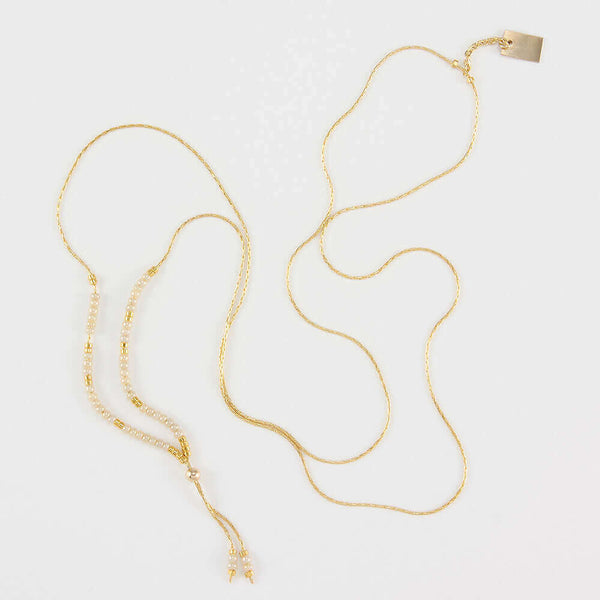 Delicate adjustable gold necklace with white and gold beads and gold rectangle drop pendant.