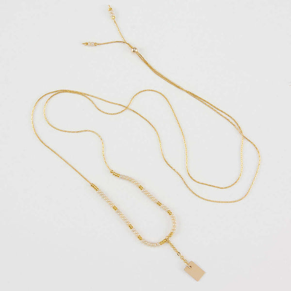 Delicate adjustable gold necklace with white and gold beads and gold rectangle drop pendant.