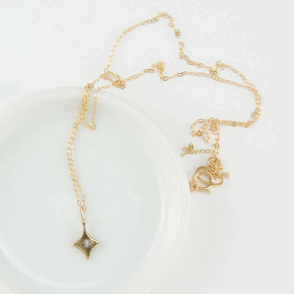 Delicate gold chain necklace with 4 point gold star pendant with inset diamond..