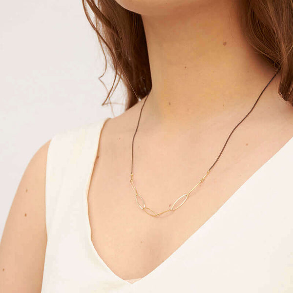 Woman wearing black oxidized silver necklace with oval gold links on the bottom, shown side angle.