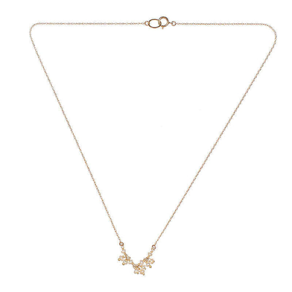 Delicate gold necklace with small pearls as pendant.
