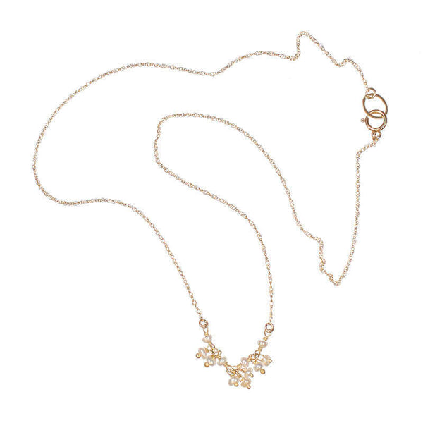 Delicate gold necklace with small pearls as pendant.