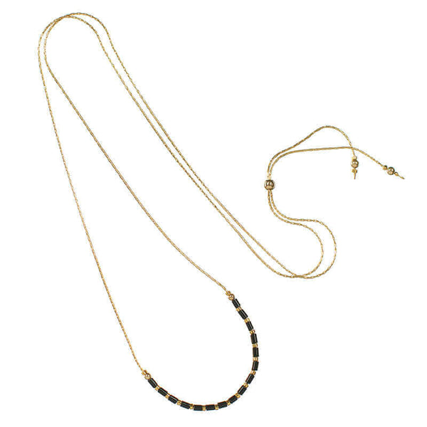 Gold necklace with black tubes and gold beads on bottom showing the slider clasp.