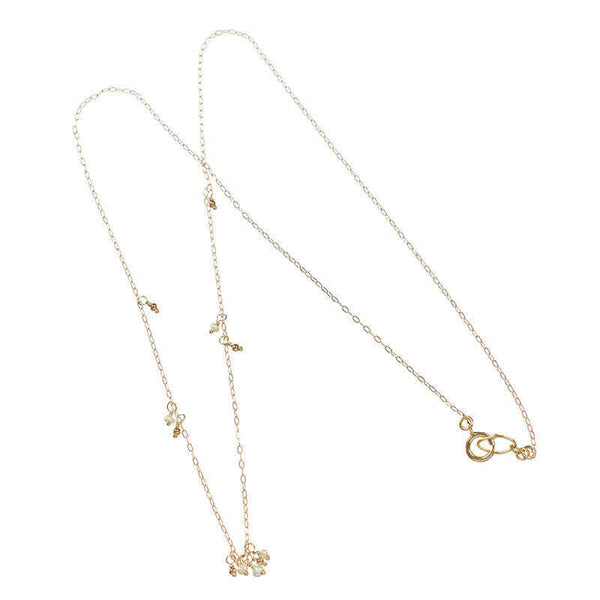 Dainty gold necklace with details of pearls along chain and pearls as pendant.