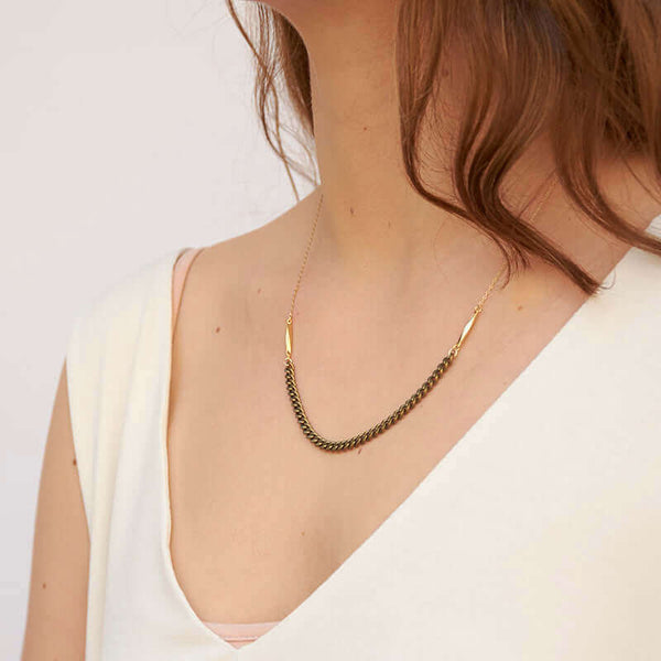 Woman wearing gold chain necklace with vintage curb chain on bottom, shown side angle.