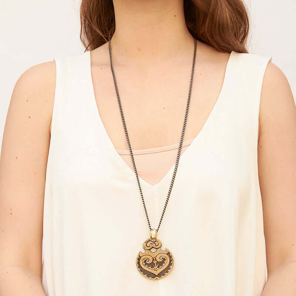 Woman wearing heavy dark chain with cast hand carved medallion.