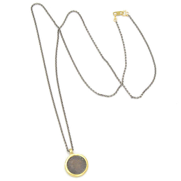 Long dark chain necklace with etched coin shaped pendant.
