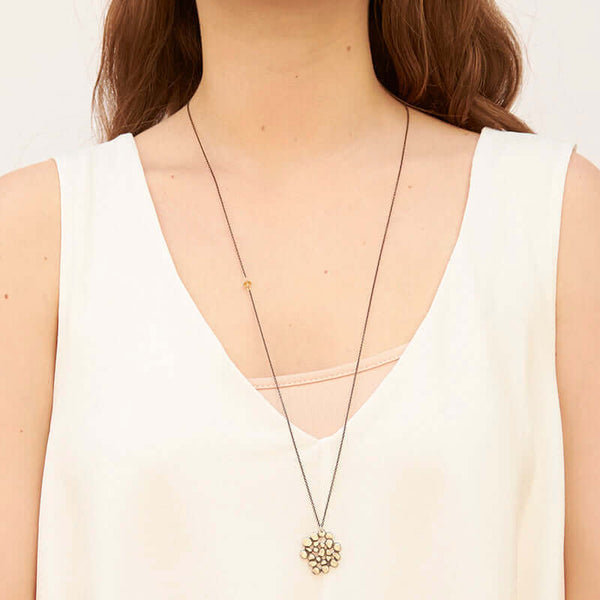 Woman wearing a dark chain necklace with cast silver tree canopy inspired pendant.
