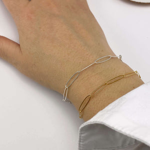 Close-up of hand wearing a gold and a silver bracelet of elongated links.