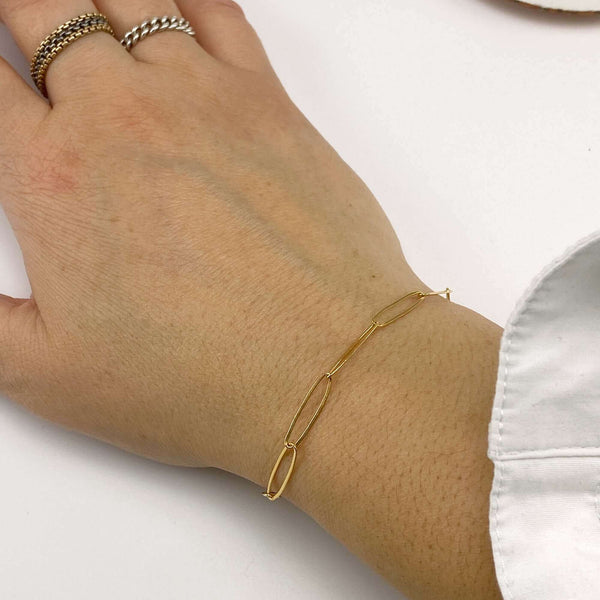 Close-up of hand wearing a gold bracelet of elongated links.