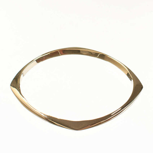 Gold bangle with rounded square shape, shown at low angle.