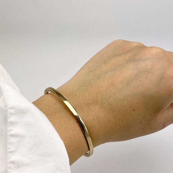 Close-up of wrist wearing brass and hand-hammered open cuff bracelet.