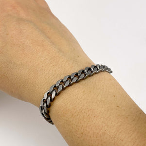 Close-up of hand wearing chunky vintage curb chain bracelet.
