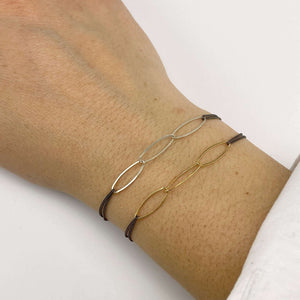 Close-up of hand wearing 2 black oxidized chain bracelet one with gold and one with silver oval links.