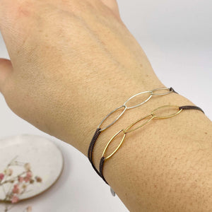 Close-up of hand wearing 2 black oxidized chain bracelet one with gold and one with silver oval links.