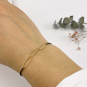 Close-up of hand wearing black oxidized chain bracelet with gold oval links.