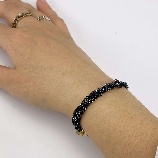 Close-up of bracelet with 3 twisted black oxidized chain on gold links and clasp.