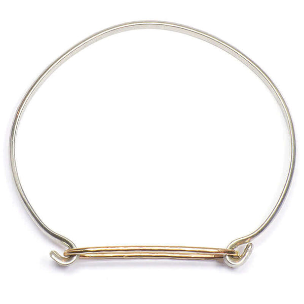 Simple bangle bracelet of gold hammered oval on silver cuff, shown from above.