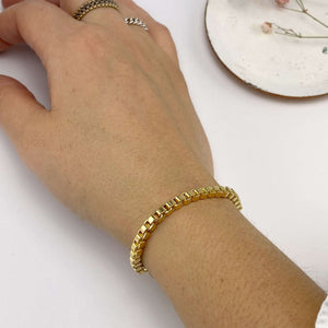 Close-up of hand wearing a chunky gold box chain bracelet.