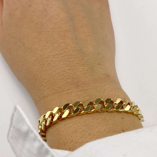 Close-up of hand wearing a chunky gold curb chain bracelet.