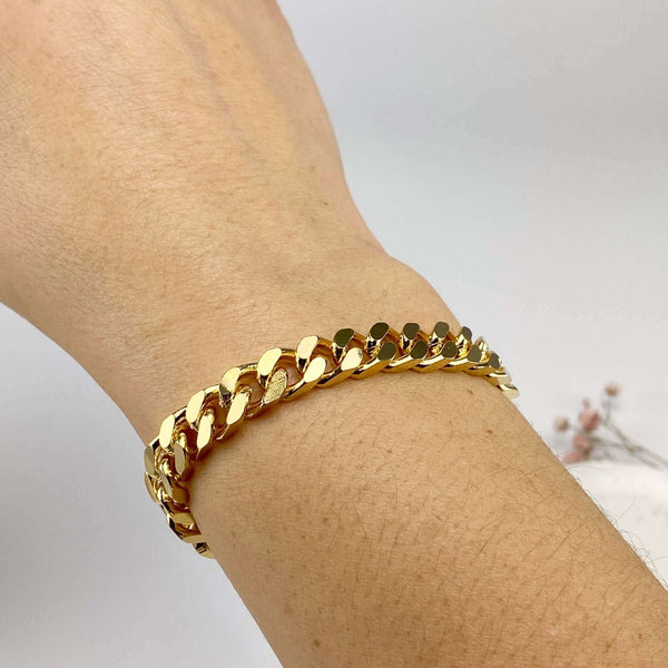 Close-up of hand wearing a chunky gold curb chain bracelet.