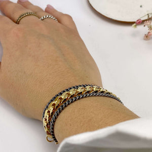 Close-up of hand wearing a uulti-chain bracelet of chunky dark and gold chain.
