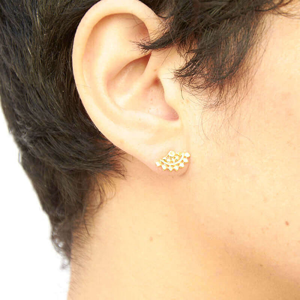 Close-up side view of woman wearing fan-shaped gold earrings with lace pattern.