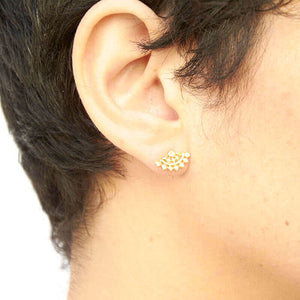 Close-up side view of woman wearing fan-shaped gold earrings with lace pattern.
