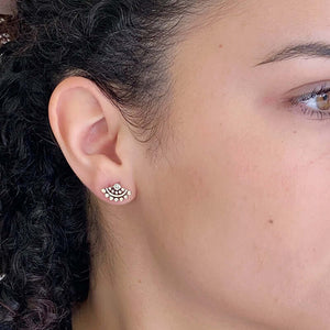 Close-up side view of woman wearing fan-shaped gold earrings with lace pattern, inset with small diamond.
